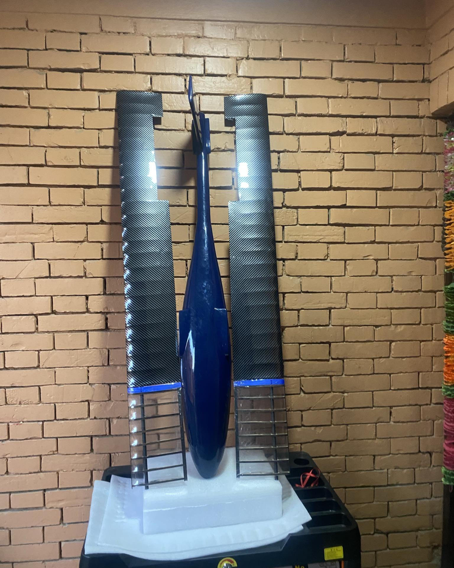 Painted blue monocoque fuselage standing between the two wing panels